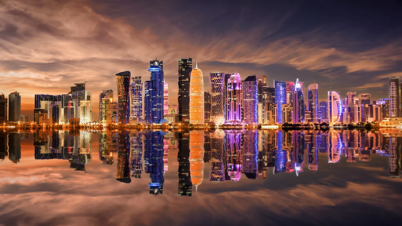 Doha’s illuminated West Bay skyline reflected in the water at dusk